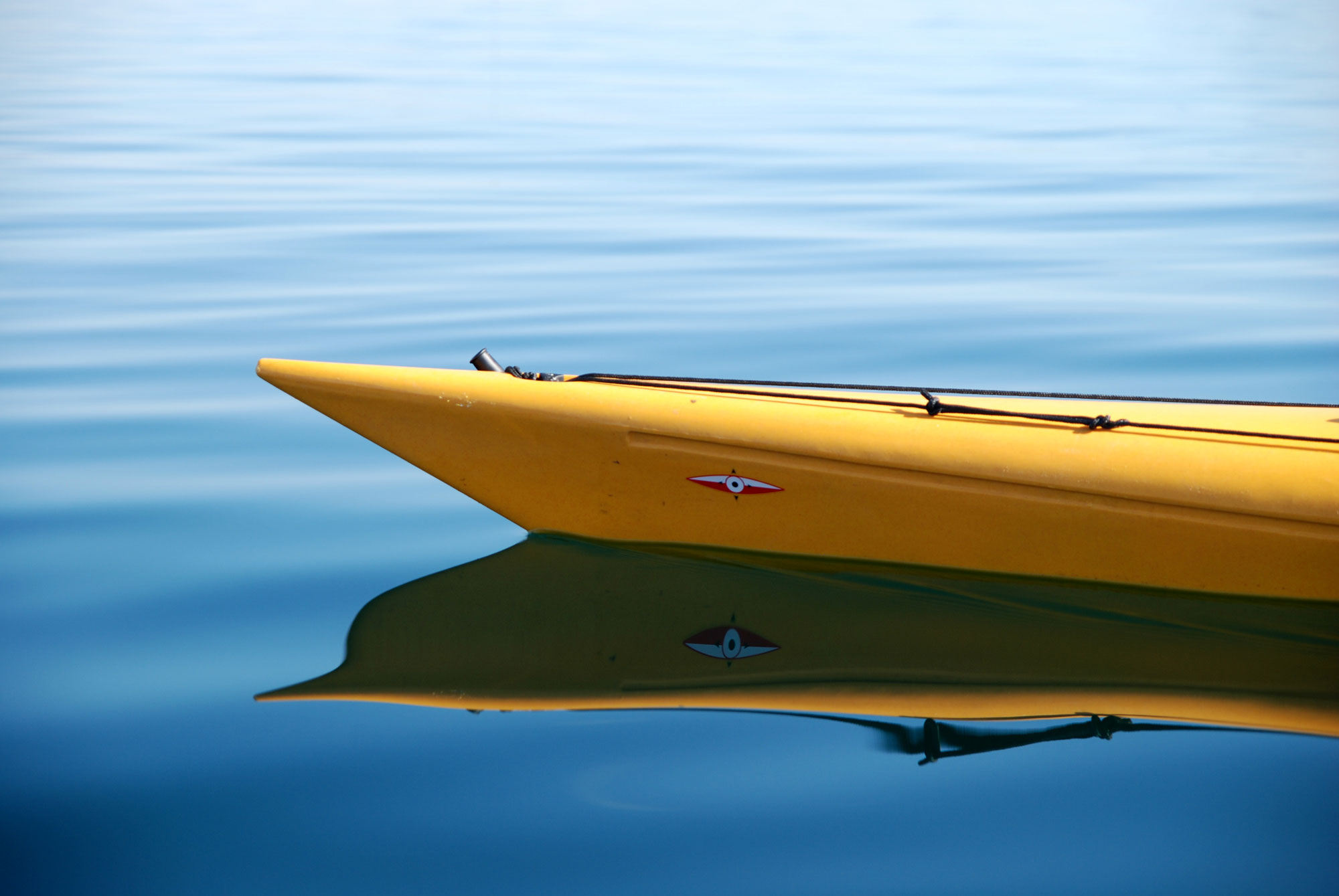 Man sieht die Spitze eines gelben Kanus auf dem Wasser.